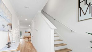 Un interior moderno con una escalera, piso de madera y un comedor con sillas y una mesa.