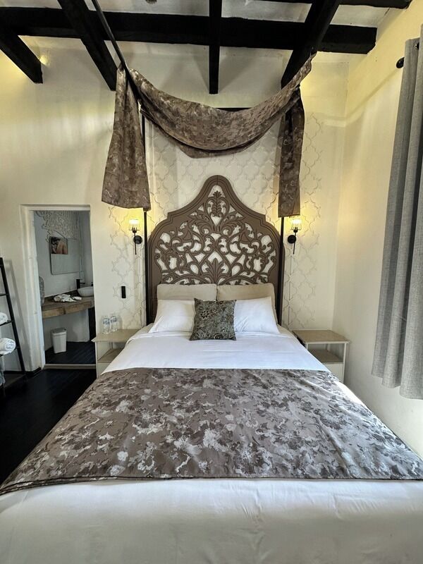 Un dormitorio con una cama grande, un cabecero decorativo y dos lámparas de noche.