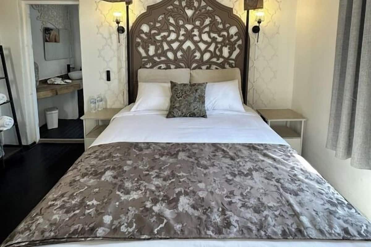 Un dormitorio con una cama grande, un cabecero decorativo y dos lámparas de noche.