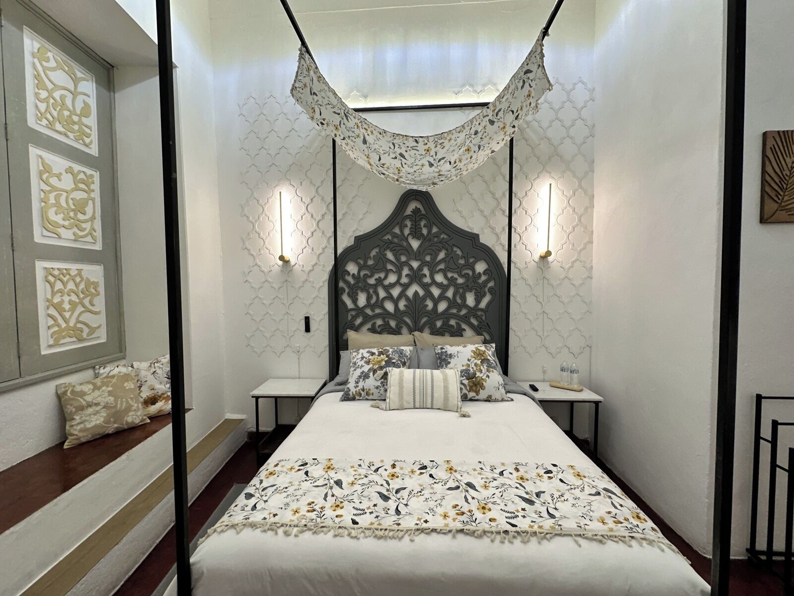 Un dormitorio con cama con dosel, paneles decorativos en la pared y lámparas de noche.