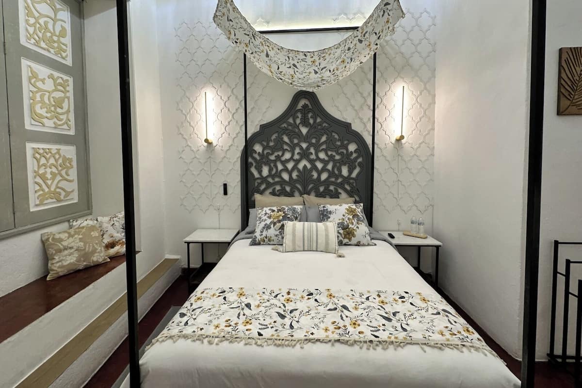 Un dormitorio con cama con dosel, paneles decorativos en la pared y lámparas de noche.