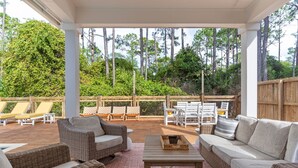 Un patio al aire libre con mobiliario de mimbre, una mesa y vistas del bosque circundante.