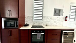 Eine kleine Küche mit Mikrowelle, Backofen und Kühlschrank.
