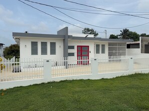 A modern building with a red door, white walls, and a white fence. - Casa Marty. Spacious 4-bedroom house in pleasant Aguadilla with cool AC breeze. (Aguadilla)