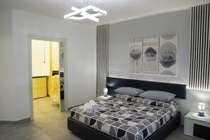 A modern bedroom with a large bed, a bedside table, a wall-mounted artwork, and a ceiling light fixture. - Vacation home a few meters from the historic center of Agrigento. (Agrigento)