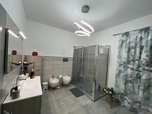 A modern bathroom with a glass-enclosed shower, a vanity with a mirror, a toilet, and a sink. - Vacation home just a few meters from the historic center of Agrigento. (Agrigento)