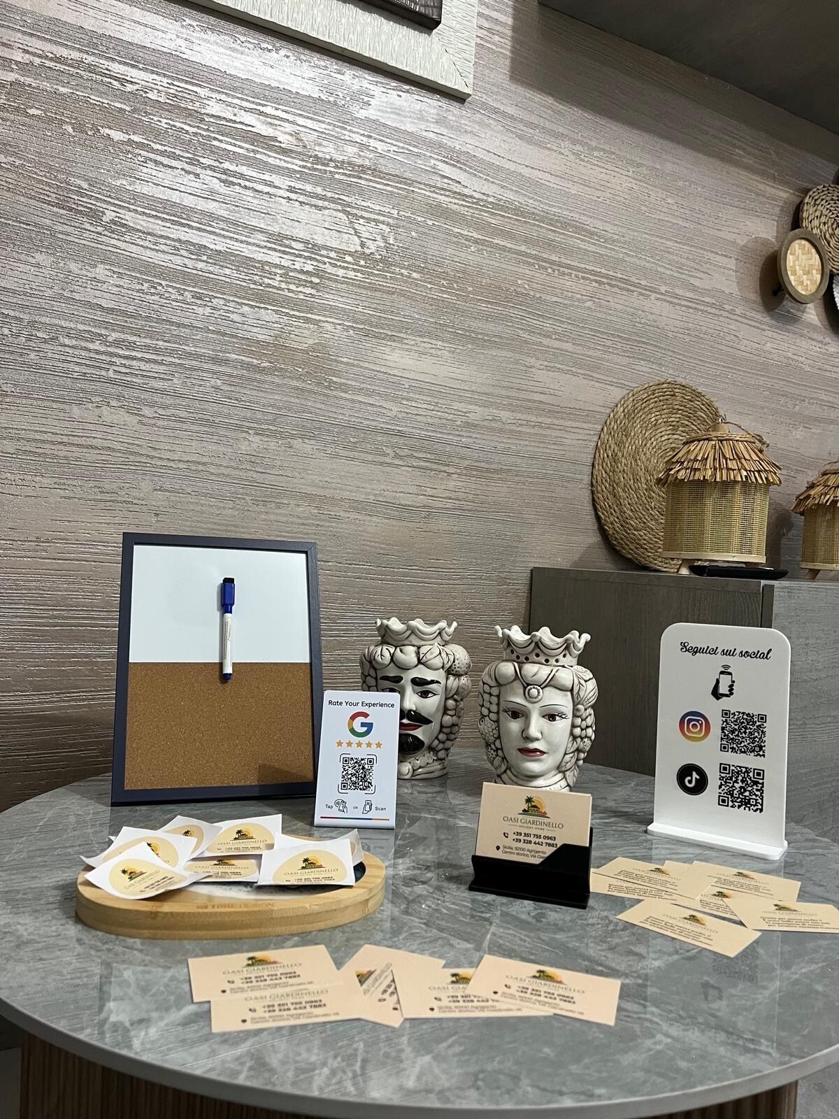 A corkboard with a pen, a QR code for rating experiences, and business cards on a marble table.
