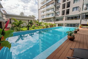 Ein modernes Hotel mit einem Dachpool im Infinity-Stil, umgeben von üppiger Vegetation und Topfpflanzen.
