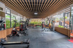 Ett gym med olika typer av träningsutrustning, stora fönster och en modern takdesign.