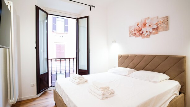Un dormitorio con cama, balcón y una obra de arte colgada en la pared.