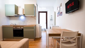 Una cocina compacta con comedor, lavadora y televisor montado en la pared.