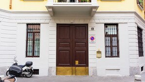 Un edificio con una puerta doble marrón grande, un pequeño balcón y un letrero que indica zona de no estacionamiento.
