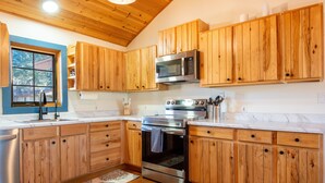 Una cucina con mobili in legno, un forno in acciaio inossidabile e un microonde.