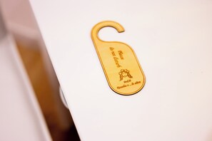 A gold-colored keychain with text and a small drawing. - Rosalia e le altre (Palermo)