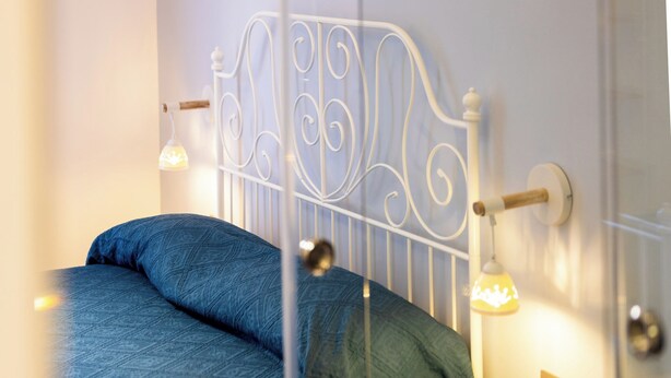 A bed with a metal headboard, two pillows, and bedside lamps. - Rosalia e le altre (Palermo)