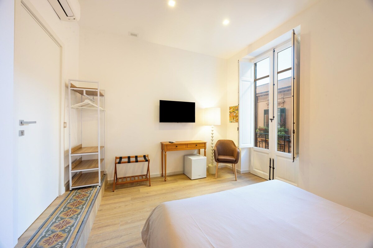 Un dormitorio con cama, escritorio, silla, televisor y armario.