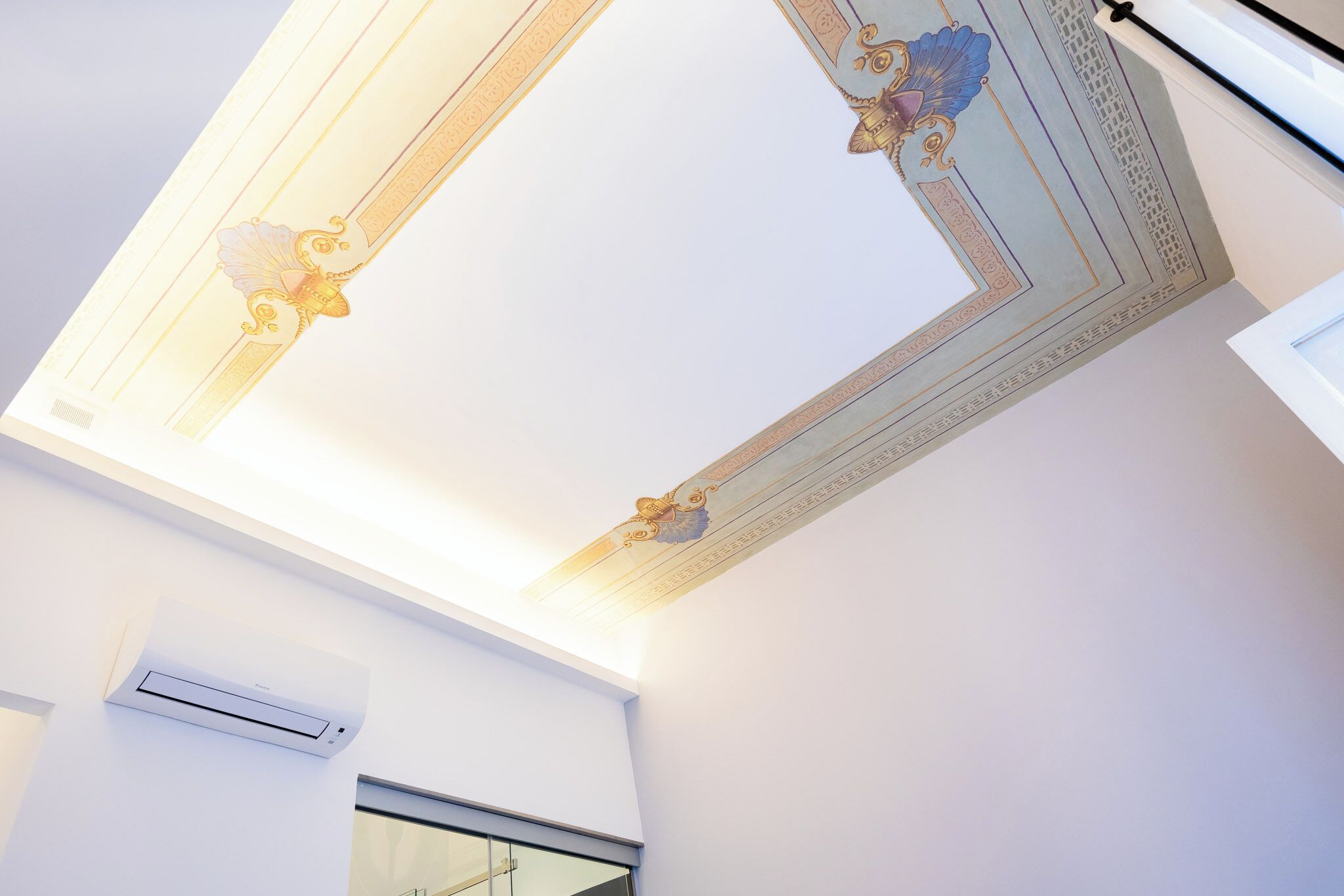 A ceiling with decorative moldings and an air conditioning unit.