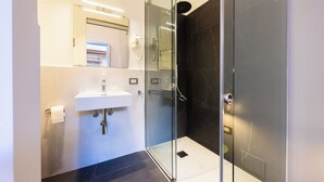A modern bathroom with a glass shower enclosure, a white sink, and a mirror above the sink. - Rosalia e le altre (Palermo)