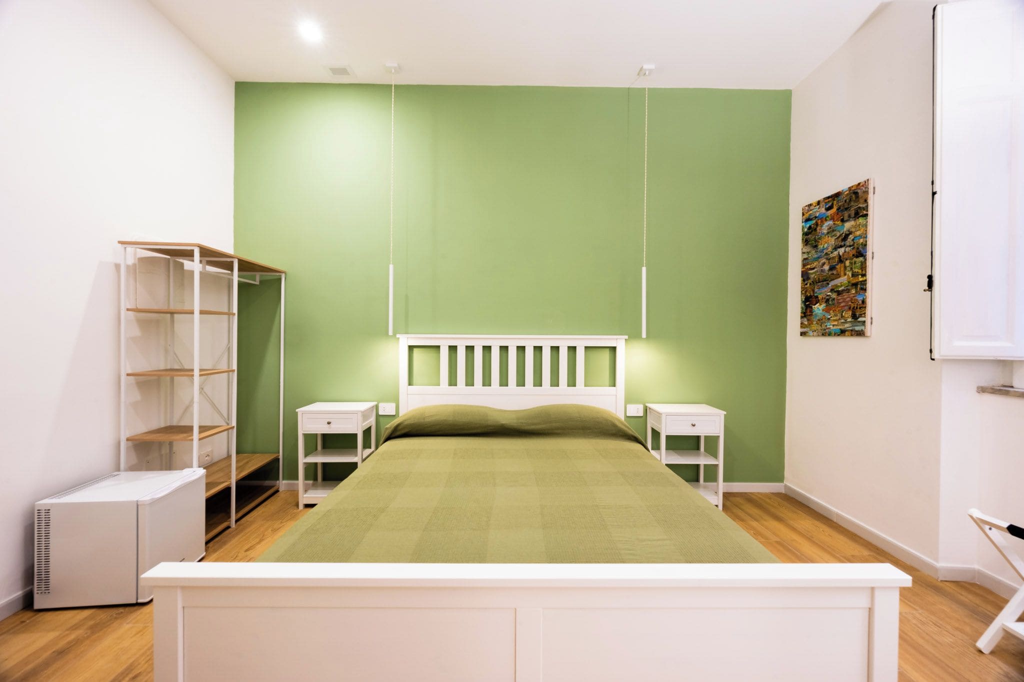 A bedroom with a bed, two bedside tables, a wardrobe, and a radiator.