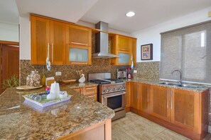 A kitchen with granite countertops, wooden cabinets, stainless steel appliances, and a granite backsplash. - ®3BR{Beach~Retreat}@Terrenas +Pool+Maid+Beachfront (Las Terrenas)