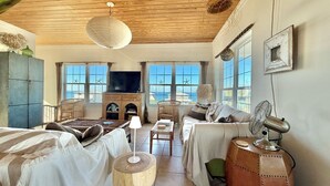 Ein gemütliches Wohnzimmer mit Kamin, großen Fenstern und Meerblick.
