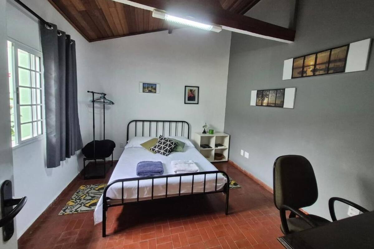 Een slaapkamer met een bed, een stoel, een bureau, een kledingkast en een raam.