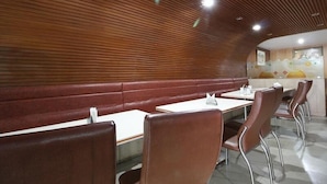 A restaurant with booths and tables, wooden paneling on the walls, and a modern interior design. - Hotel Sri Sai Regency (Hyderabad)