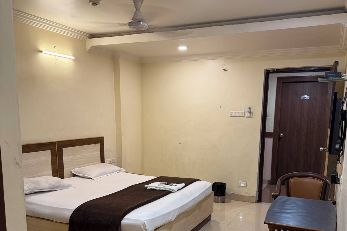 A hotel room with a bed, a desk, a chair, and a door.