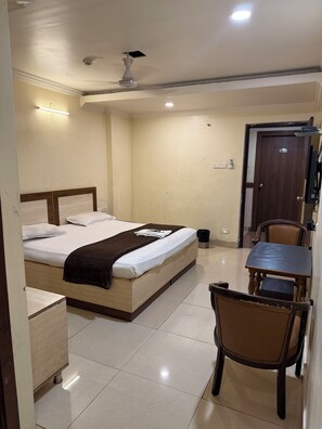 Une chambre d’hôtel avec un lit, un bureau, une chaise et une porte.