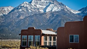 A building with large windows and a mountain backdrop. - Bluebird Trail Retreat: Off-Grid & Dark Skies (Saguache County)