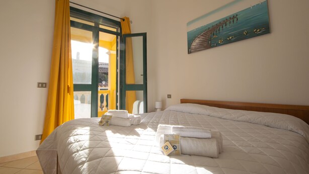 Quarto de hotel com uma cama, um quadro de um cais e vista para um edifício pela janela.