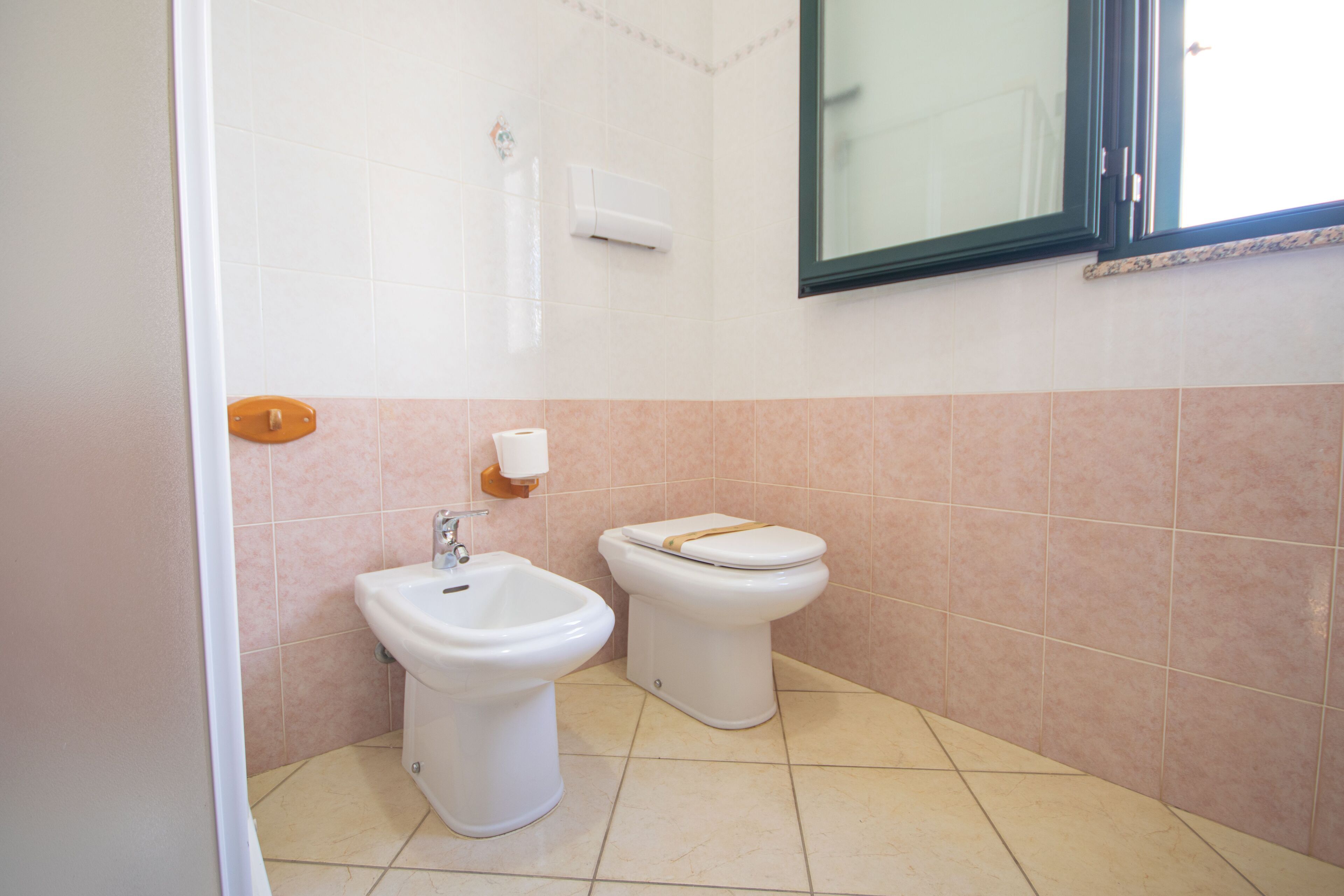 Ein Badezimmer mit einer Bidet, Toilette und einem Spiegel.
