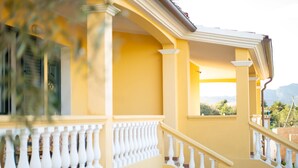Edifício amarelo com grades brancas e escadaria.