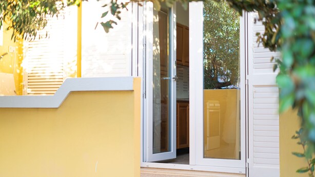 A yellow exterior wall with a sliding glass door leading to a kitchen area. - Villa Mirto 2 - Two Bedroom Apartment, Sleeps 4 (San Giovanni)
