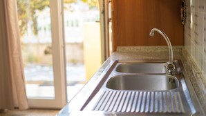 A kitchen with a stainless steel sink, a window with curtains, and a tiled backsplash. - Villa Mirto 2 - Two Bedroom Apartment, Sleeps 4 (San Giovanni)