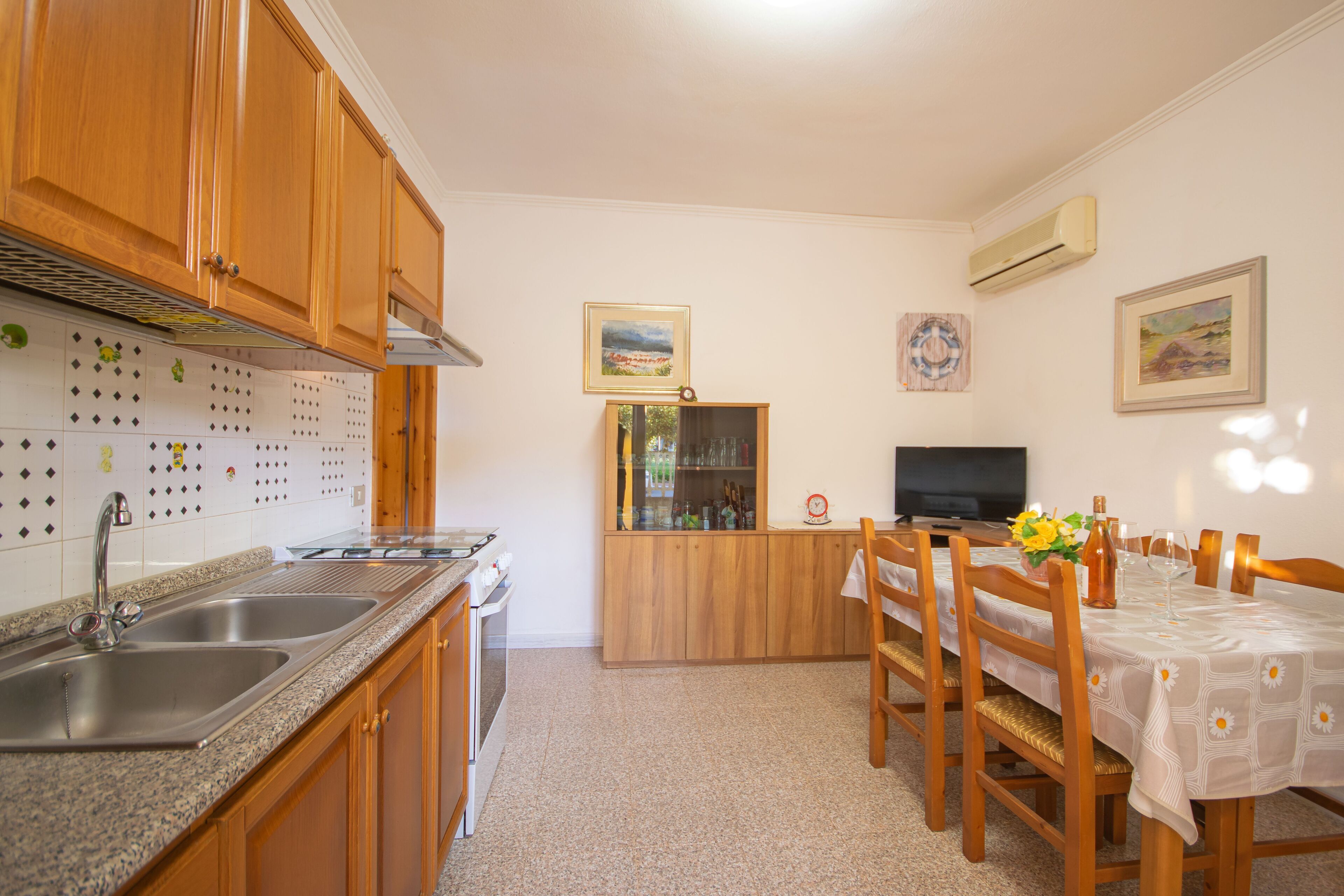 A compact kitchen with wooden cabinets, a granite countertop, and a dining area with a table set for two.
