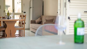 Et spiseområde med et bord, stole og en sofa. Et køleskab er synligt i baggrunden.