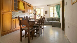 A spacious kitchen with wooden cabinets and a dining area with a table and chairs. - Le due palme - Three Bedroom Apartment, Sleeps 6 (La Caletta)