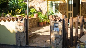 A stone entrance with a metal gate, potted plants, and a stone wall. - Le due palme - Three Bedroom Apartment, Sleeps 6 (La Caletta)
