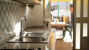A kitchen with a stainless steel sink, a tiled backsplash, and a view of the outside through an open door. - Le due palme - Three Bedroom Apartment, Sleeps 6 (La Caletta)