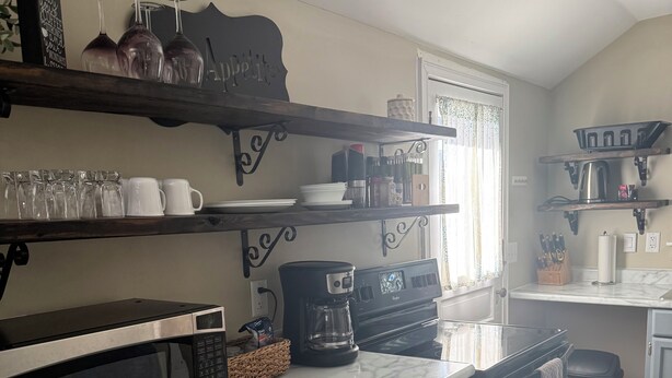 A kitchen with grey cabinets, a marble countertop, a coffee maker, and a microwave. - Charming cottage in central Lafayette 8 min to Purdue (Lafayette)