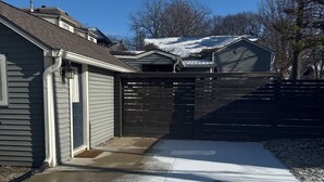 A residential driveway with a garage, a covered patio area, and a wooden fence. - Charming cottage in central Lafayette 8 min to Purdue (Lafayette)