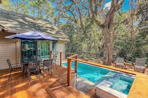 A wooden deck with a pool, outdoor furniture, and a covered seating area.