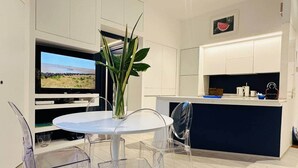 A modern kitchen with a central island, a dining area with clear chairs, and a TV displaying a landscape. - Hyper Center, 2 PP, Place Masséna,Beach: 7min,AC (Nice)