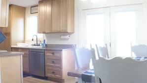 Une cuisine dotée de meubles en bois, d’un lave-vaisselle, d’un évier et d’un coin repas avec une table et des chaises.