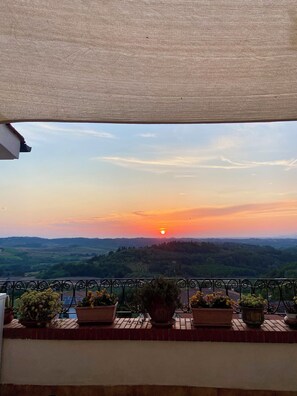 A balcony with potted plants and a view of a sunset over rolling hills. - Charmant Morrona – The Sweet Life in Tuscany (Morrona pisa)