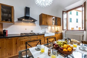 Eine moderne Küche mit Holzschränken, einem Gasherd und einem Essbereich mit gedecktem Tisch für das Frühstück.