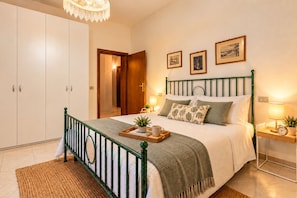 A bedroom with a bed, bedside tables, a wardrobe, and a chandelier. - Charmant Morrona – The Sweet Life in Tuscany (Morrona pisa)