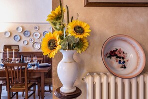 A dining table set with plates, glasses, and a vase with sunflowers. - Charmant Morrona – The Sweet Life in Tuscany (Morrona pisa)
