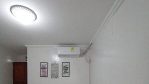 A small, clean room with two single beds, a white air conditioning unit, and a door to another room. - Miami Beach Hostel (Cartagena de Indias)